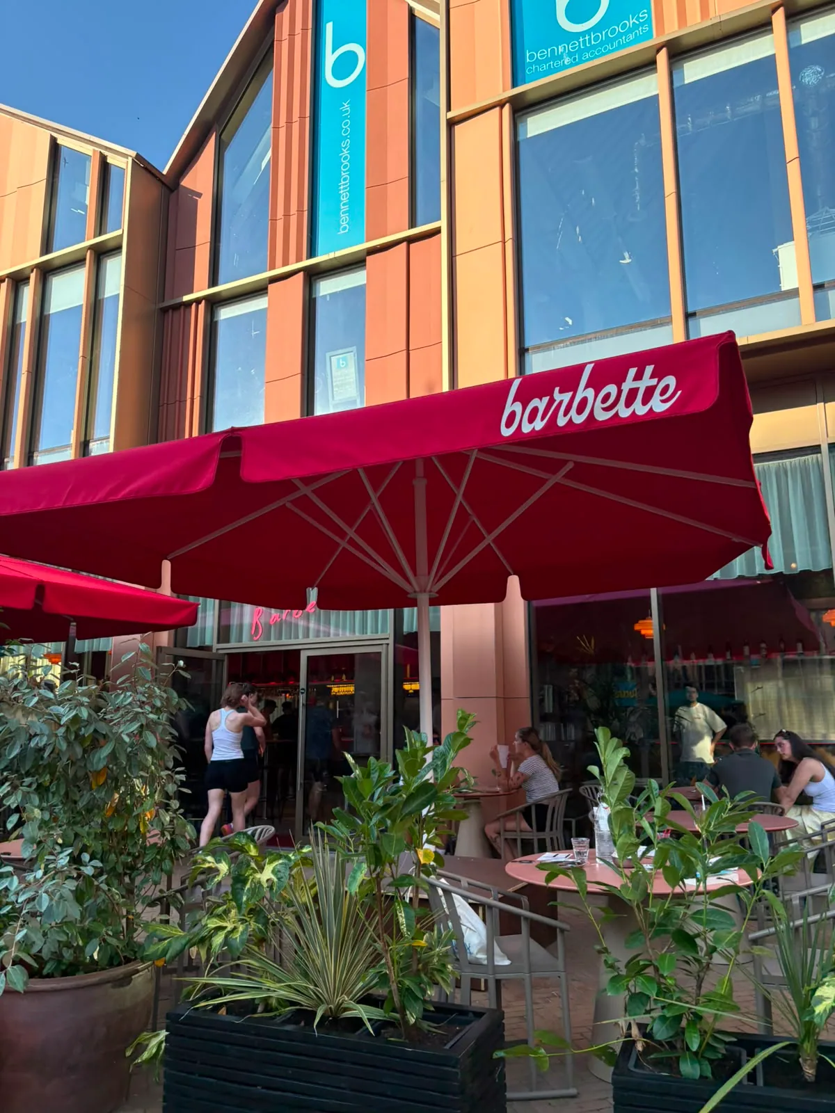 Outdoor tables and red Barbette umbrellas outside Café Barbette